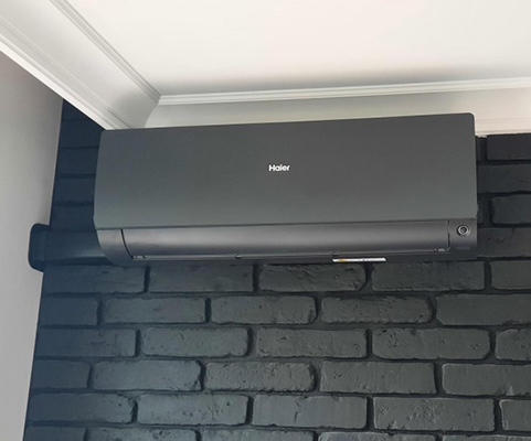 Ciemna jednostka wewnętrzna Haier zamontowana na dekoracyjnej ścianie w Rzeszowie