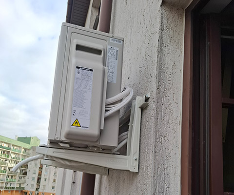 Jednostka zewnętrzna klimatyzacji na białych konsolach — Warszawa, budynek wielorodzinny