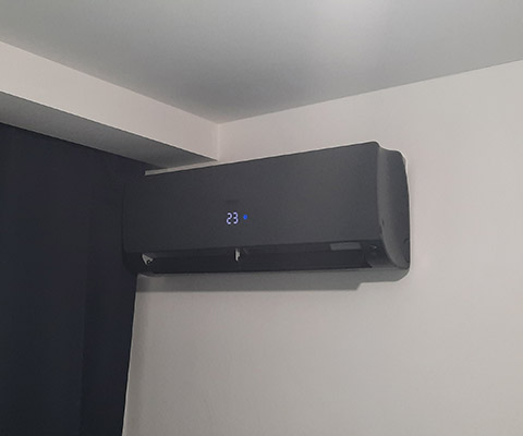 Jednostka wewnętrzna ciemnego klimatyzatora zamontowana w sypialni w Łomży